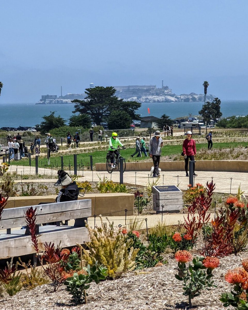 People walking and cycling through Presidio Tunnel Tops with Alcatraz across the bay